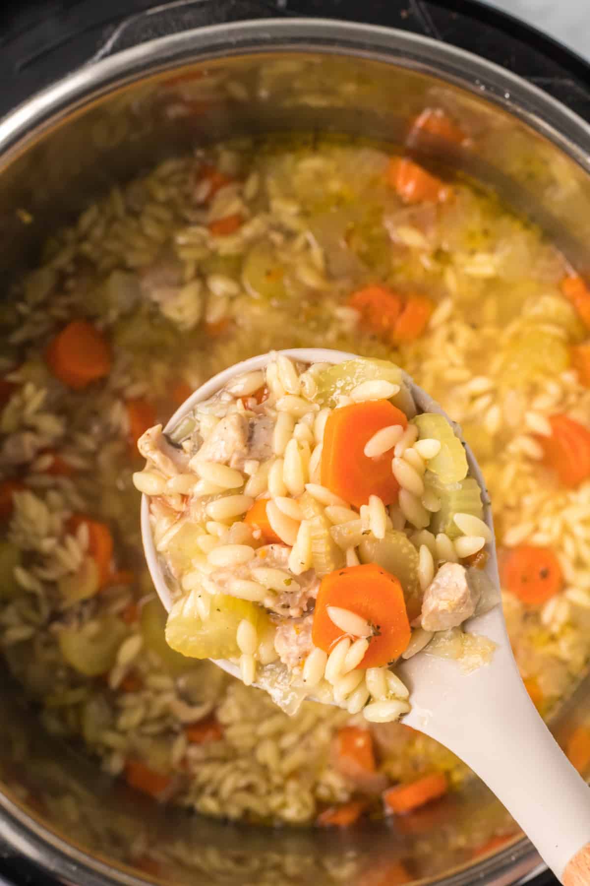 closeup of the ninja chicken soup with orzo noodles on a serving spoon