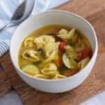 veggie tortellini soup in a white bowl with a spoon