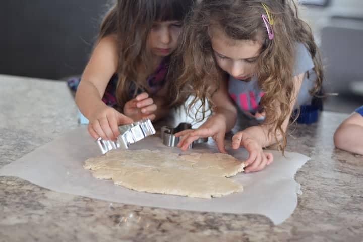 two little girls using cookie cutters to make salt dough ornaments 