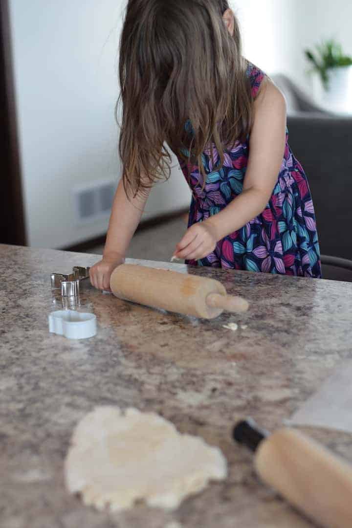 little girl rolling out salt dough on countertop