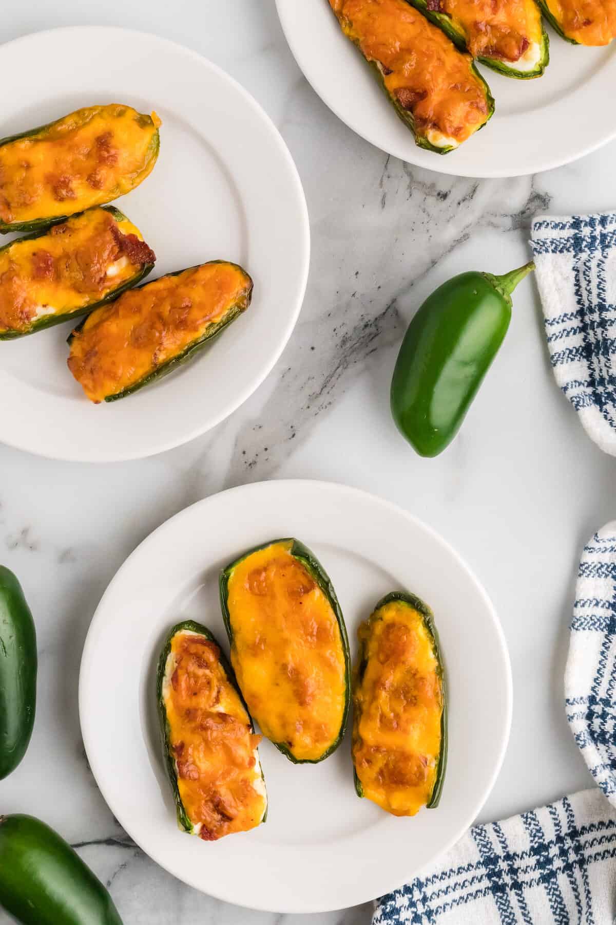three white plates filled with keto jalapeno poppers. 