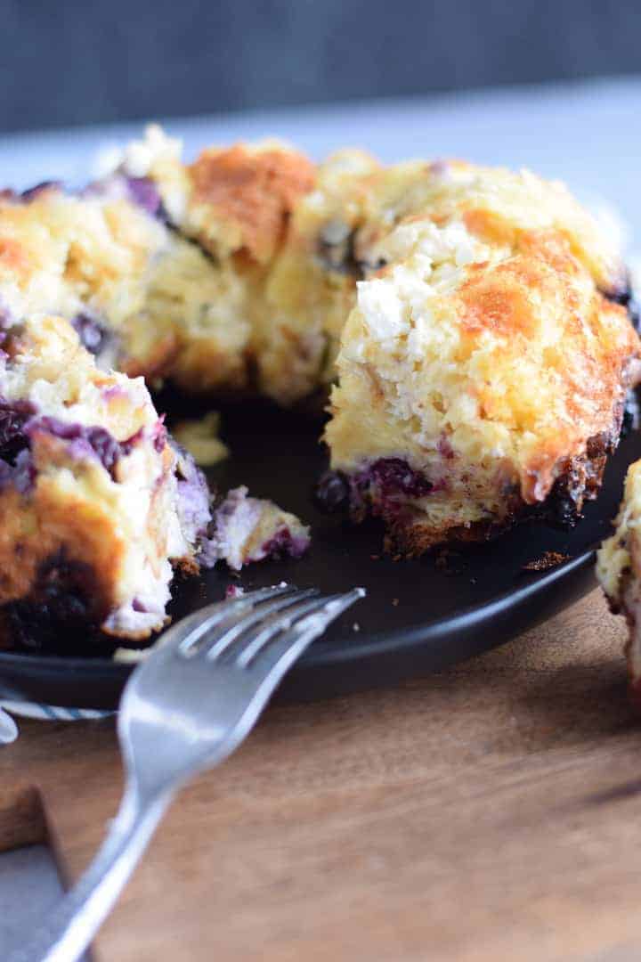 blueberry cream cheese bread pudding on a black plate with a fork