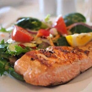 salmon over salad on a white plate