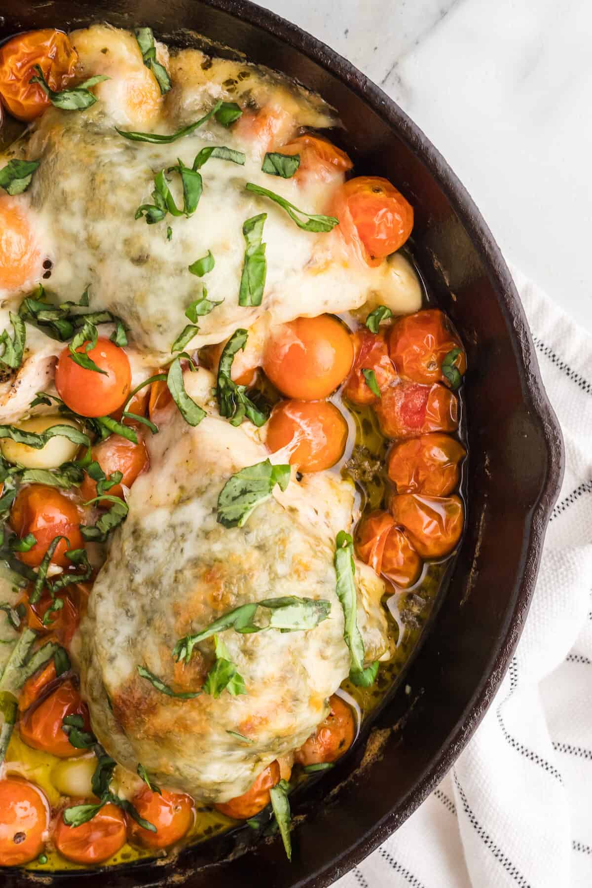 cast iron skillet with the finished keto chicken caprese recipe.