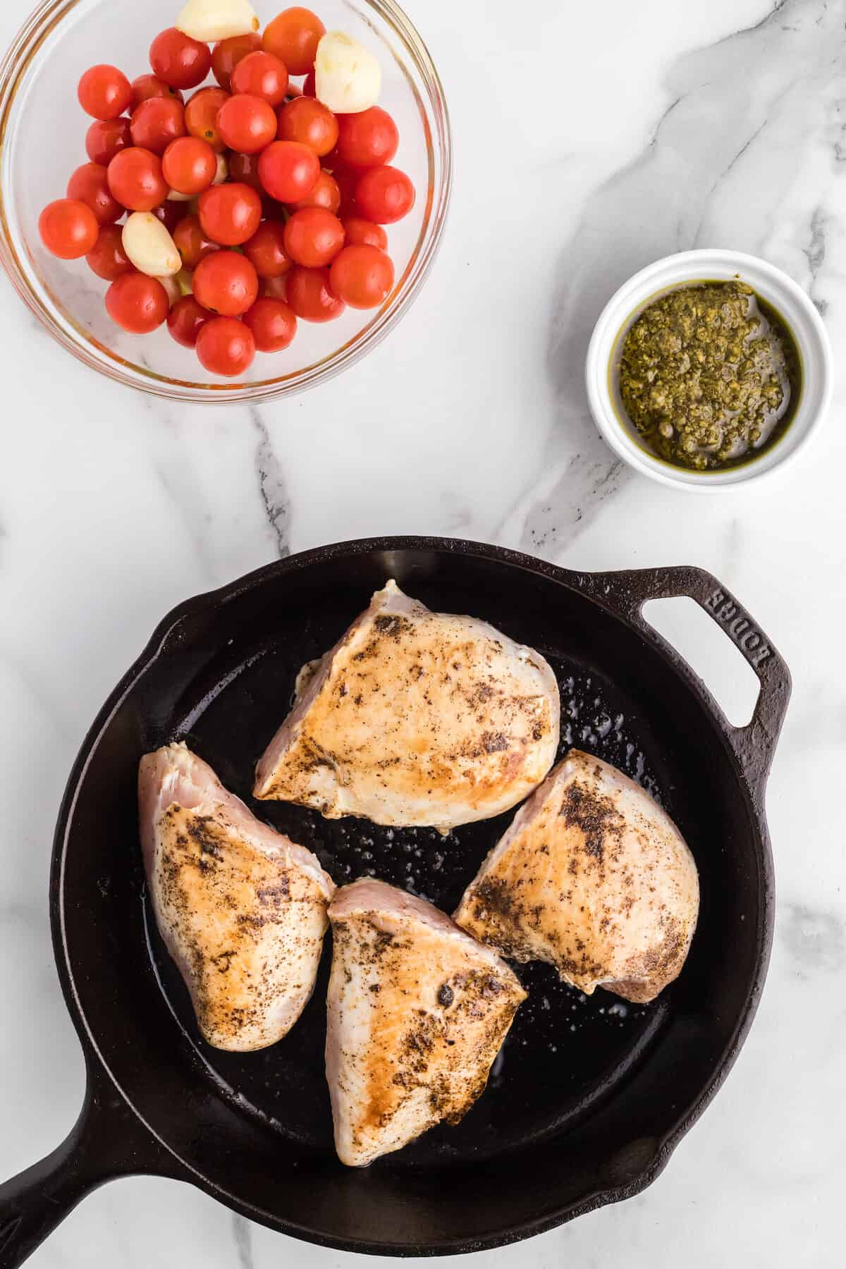 cast iron skillet with the cooked chicken breasts.