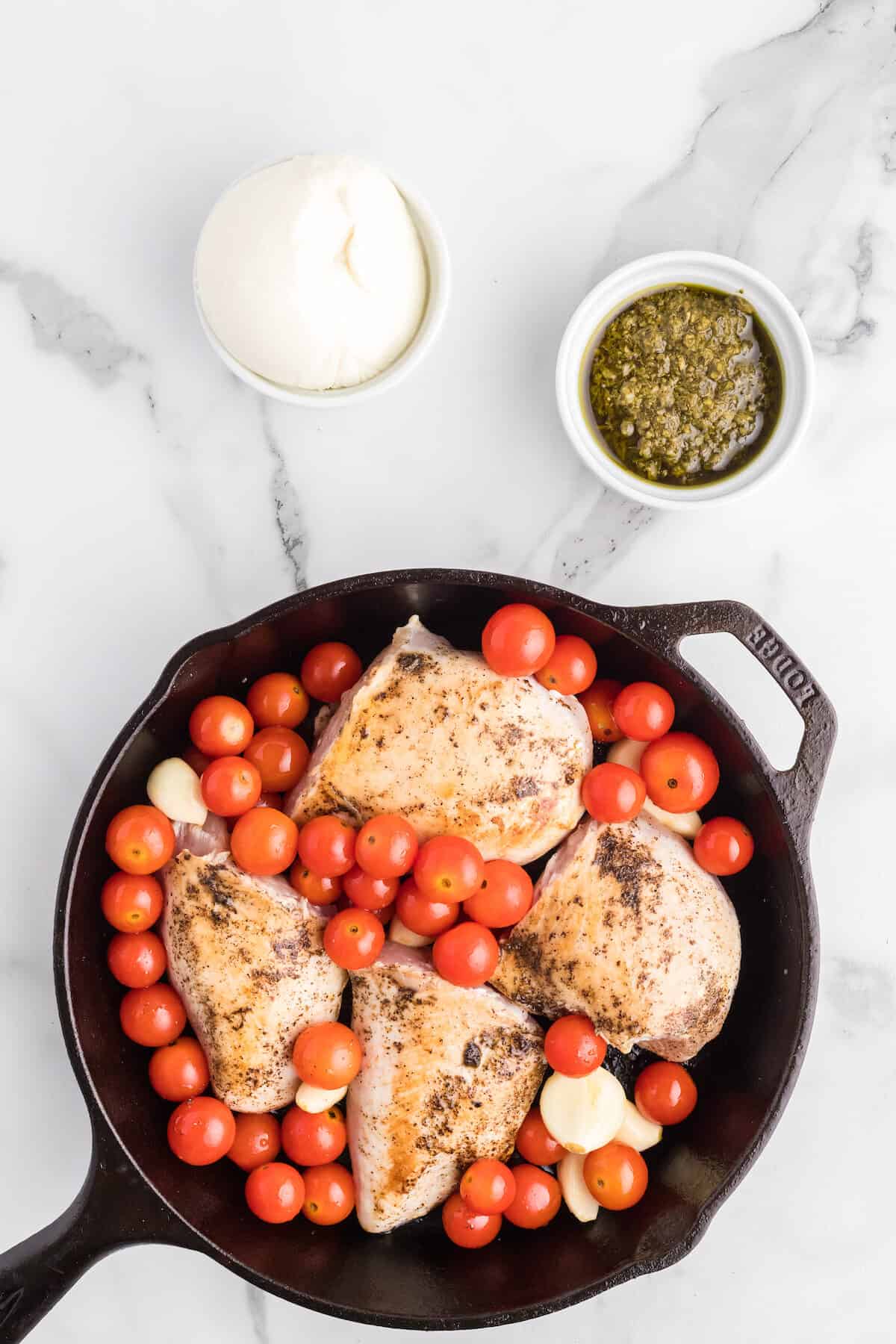 tomatoes and garlic added to the cast iron skillet with the chicken breasts.