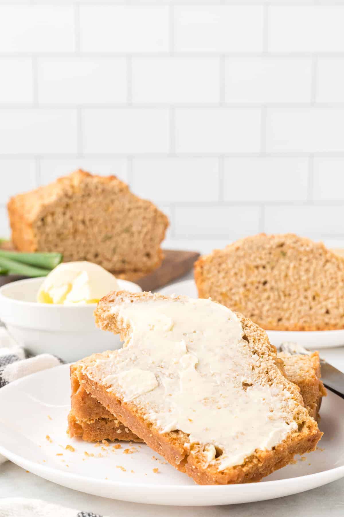 slices of beer bread on white plates with butter spread over top