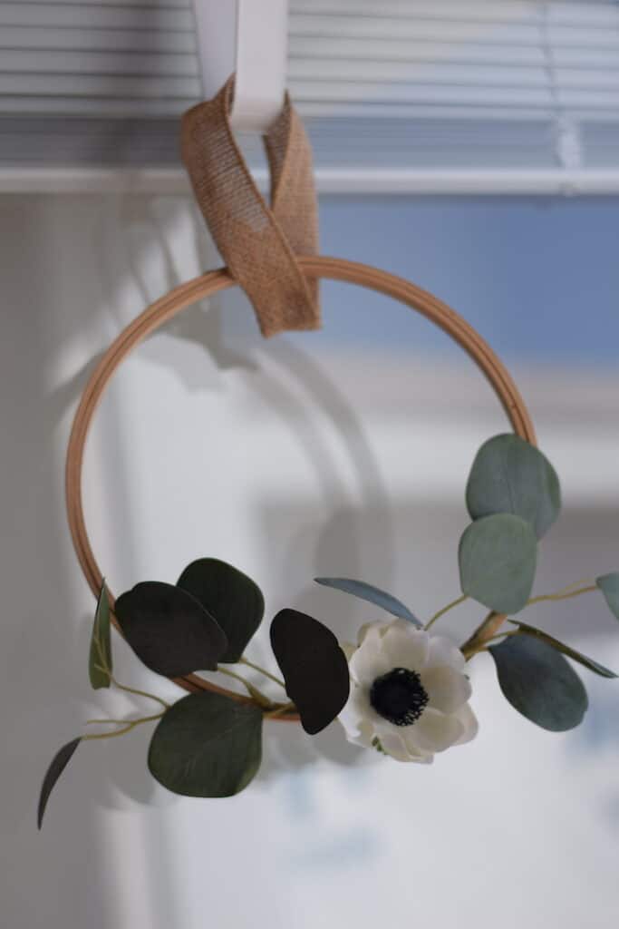 embroidery hoop wreath with white flower and eucalyptus hanging on door with hook