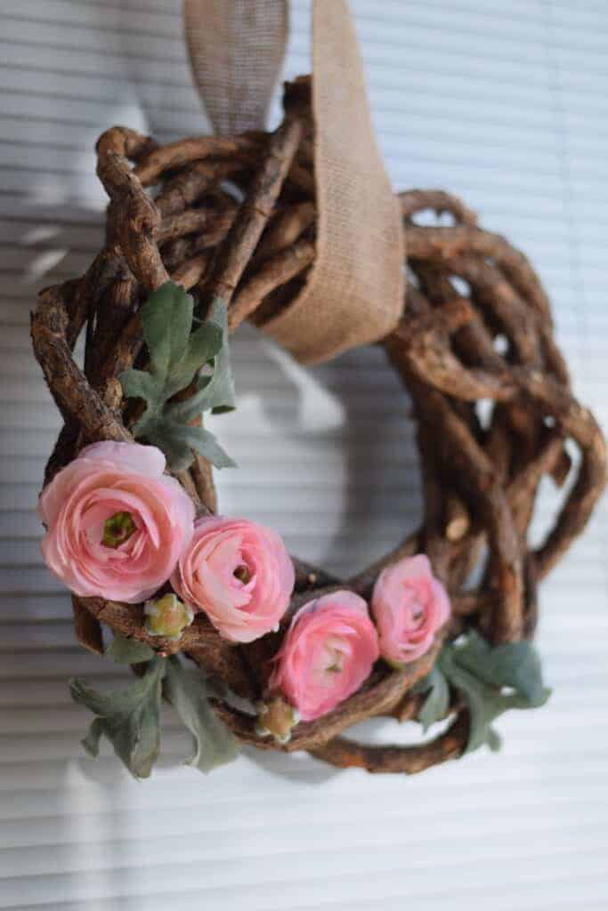 pink floral wreath with rustic branches hanging on door