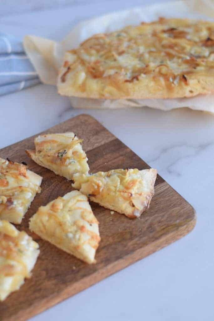 gorgonzola and caramelized onion pizza sliced and on a wooden cutting board