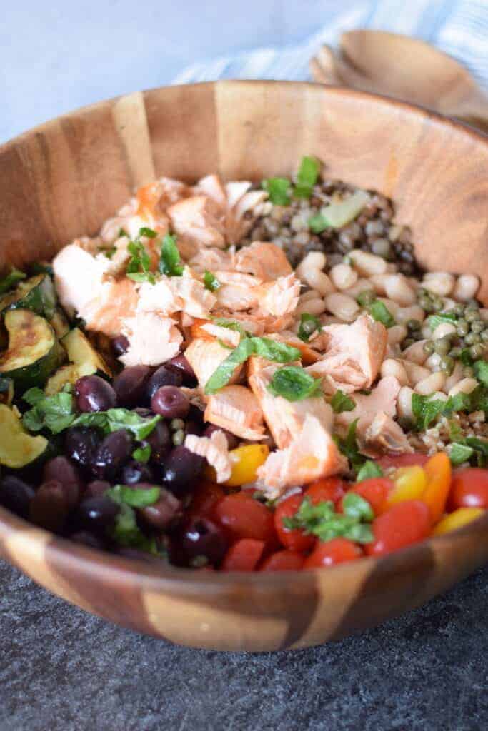 salmon grain bowl in a wooden bowl with serving utensils