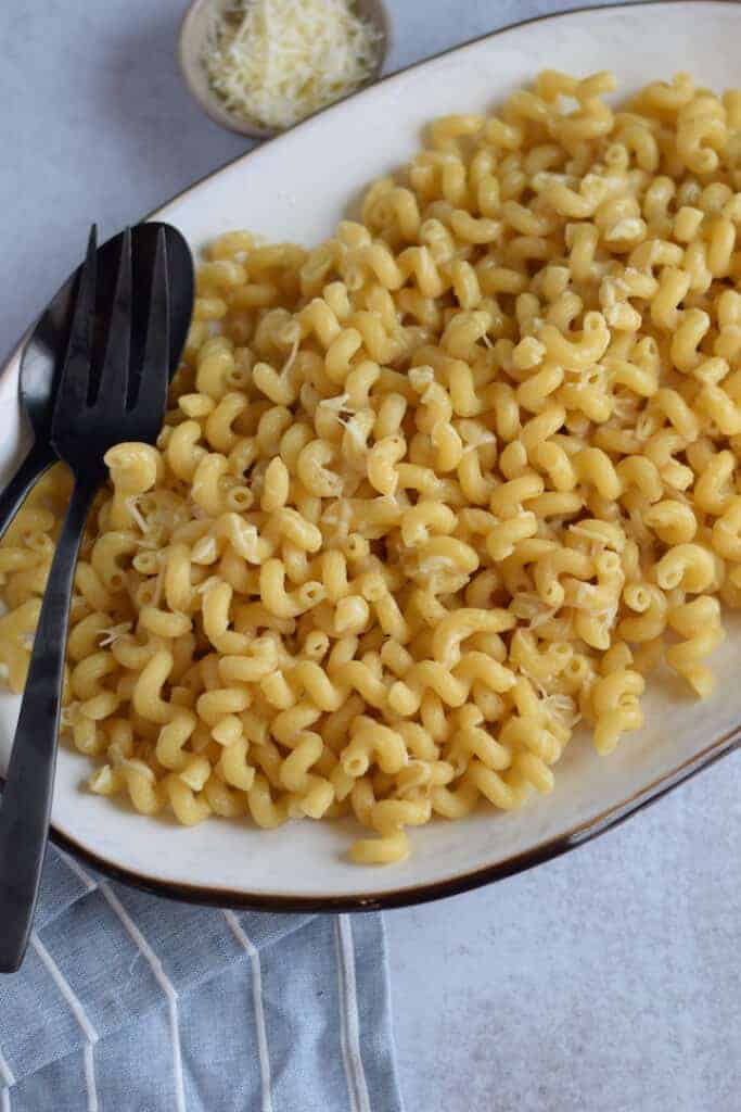 easy Parmesan and butter pasta recipe on a white platter with black serving utensils 