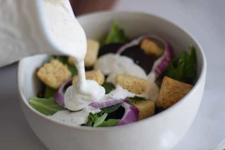 pouring the buttermilk ranch over a salad from a small cruet