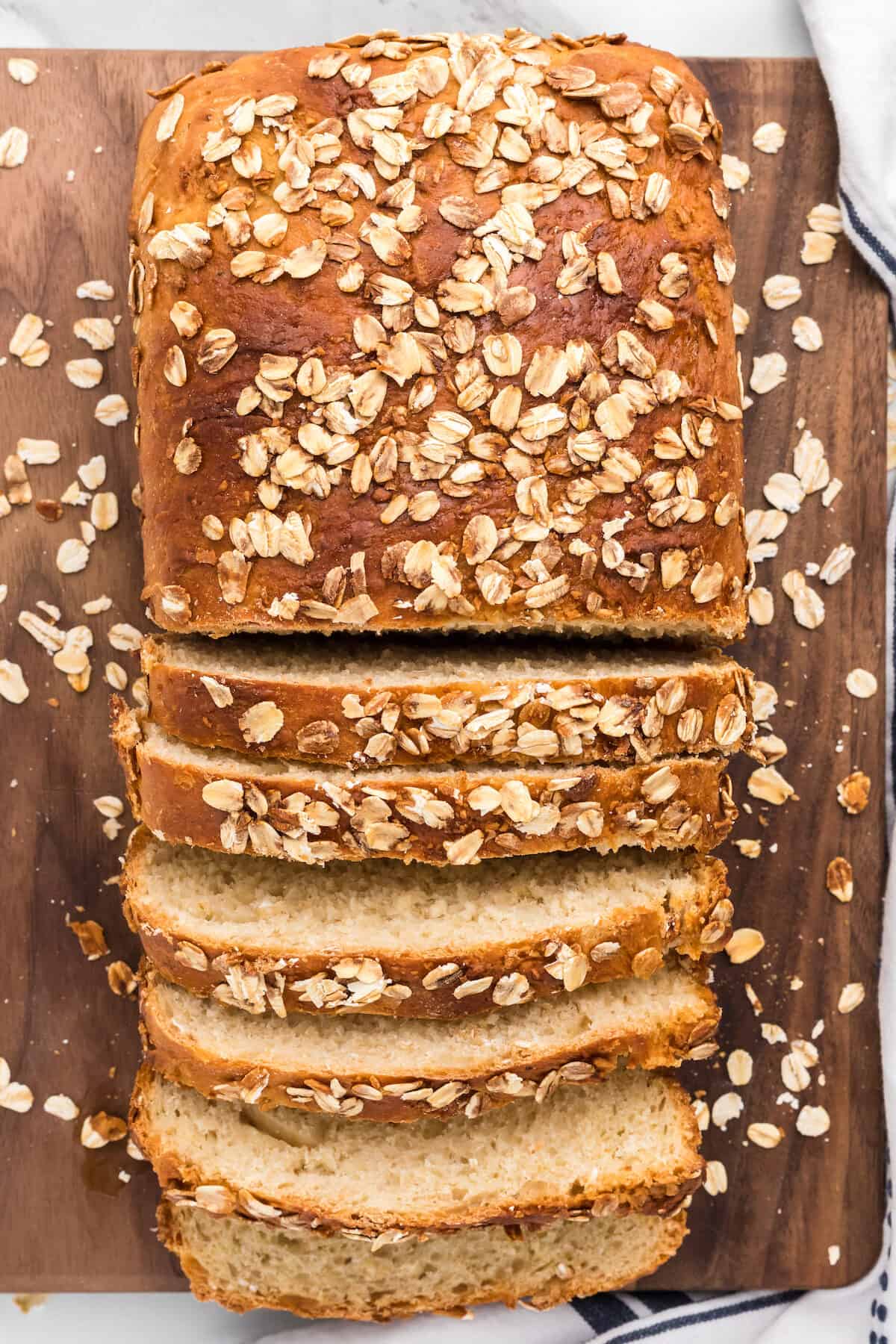 half of the honey oat bread sliced on a wooden cutting board.