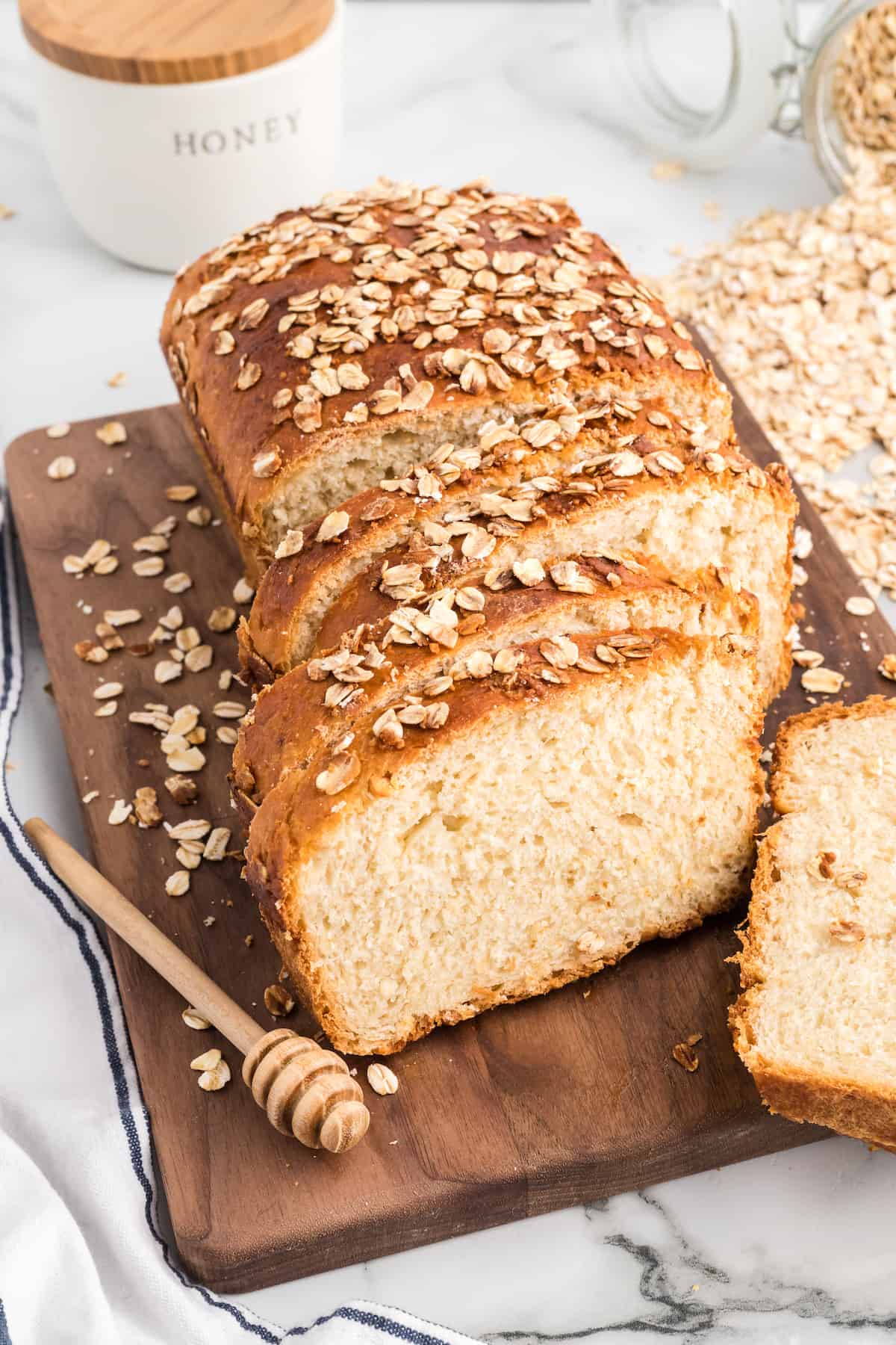 slices of honey oat bread on a wooden cutting board.