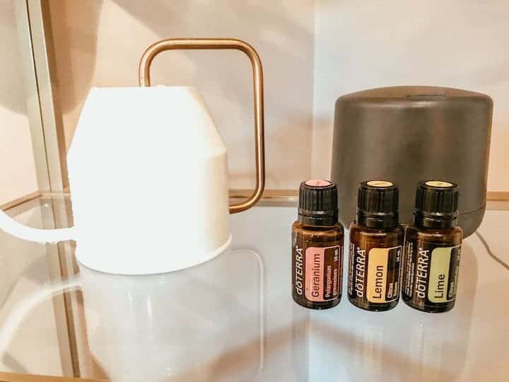 watering can and essential oils on a glass shelf