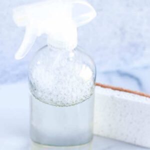 white sponge and clear glass spray bottle with homemade cleaners