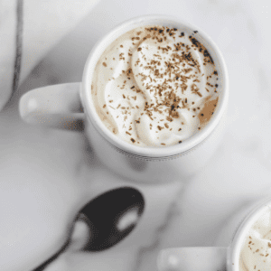homemade latte in a white mug with whipped cream on top