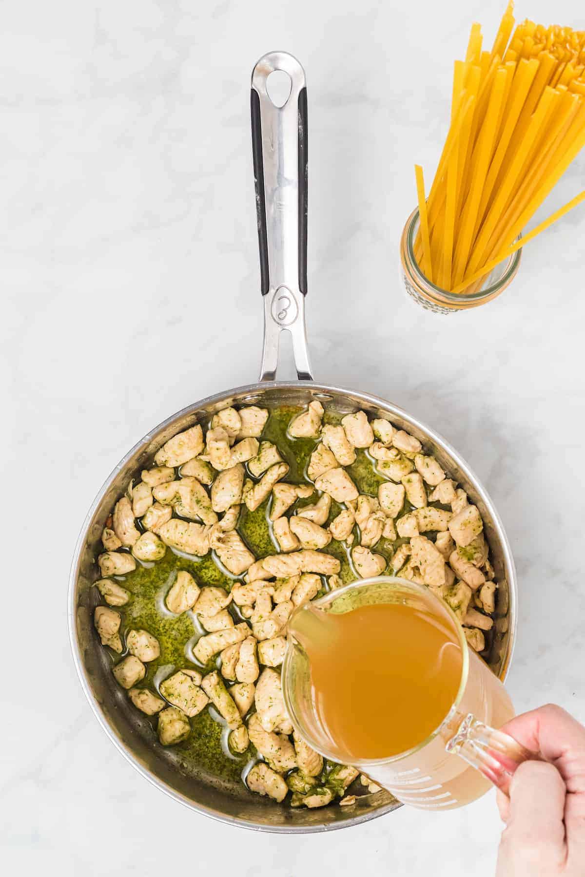 adding chicken broth to the skillet