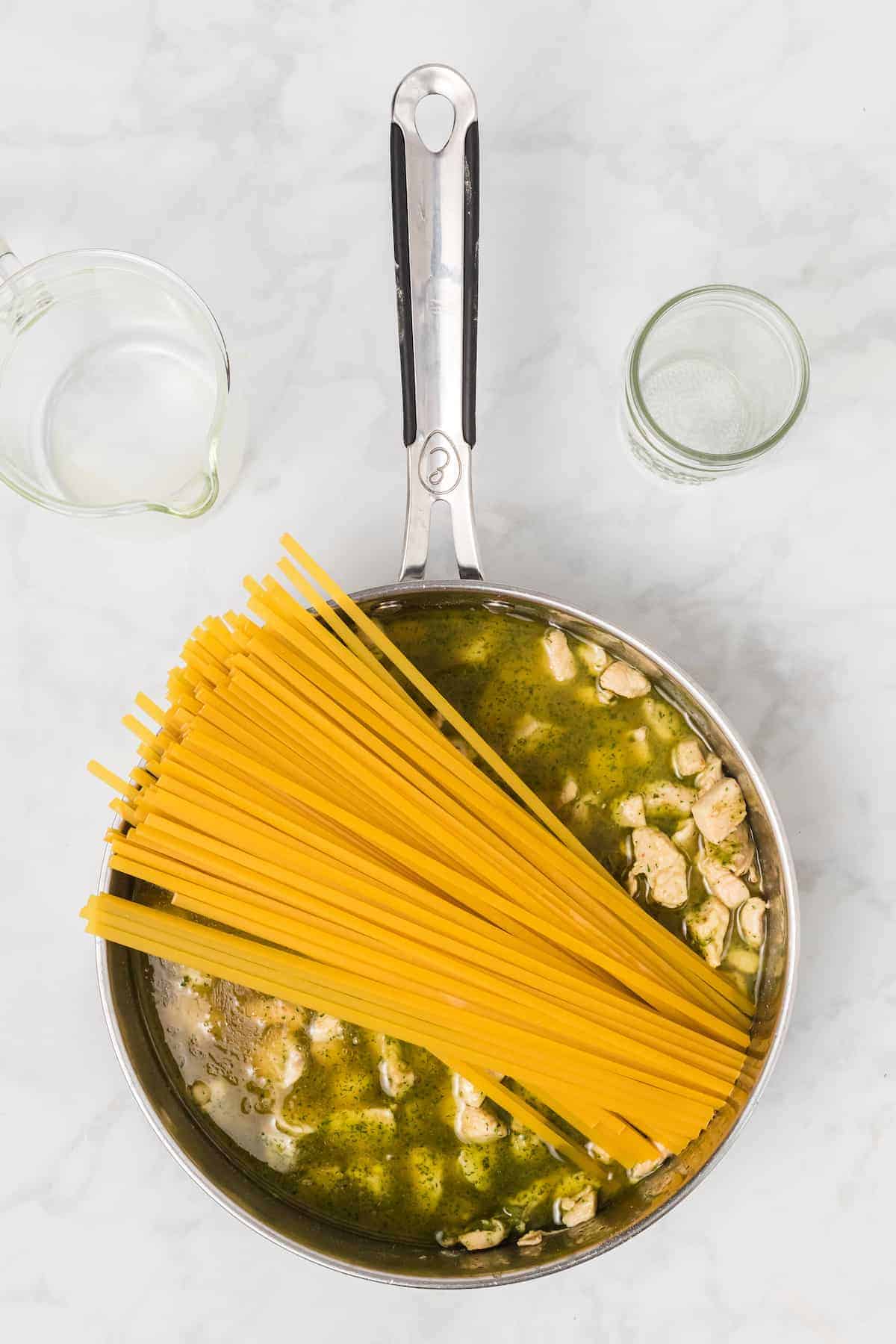 pasta added to the skillet with the cooked chicken