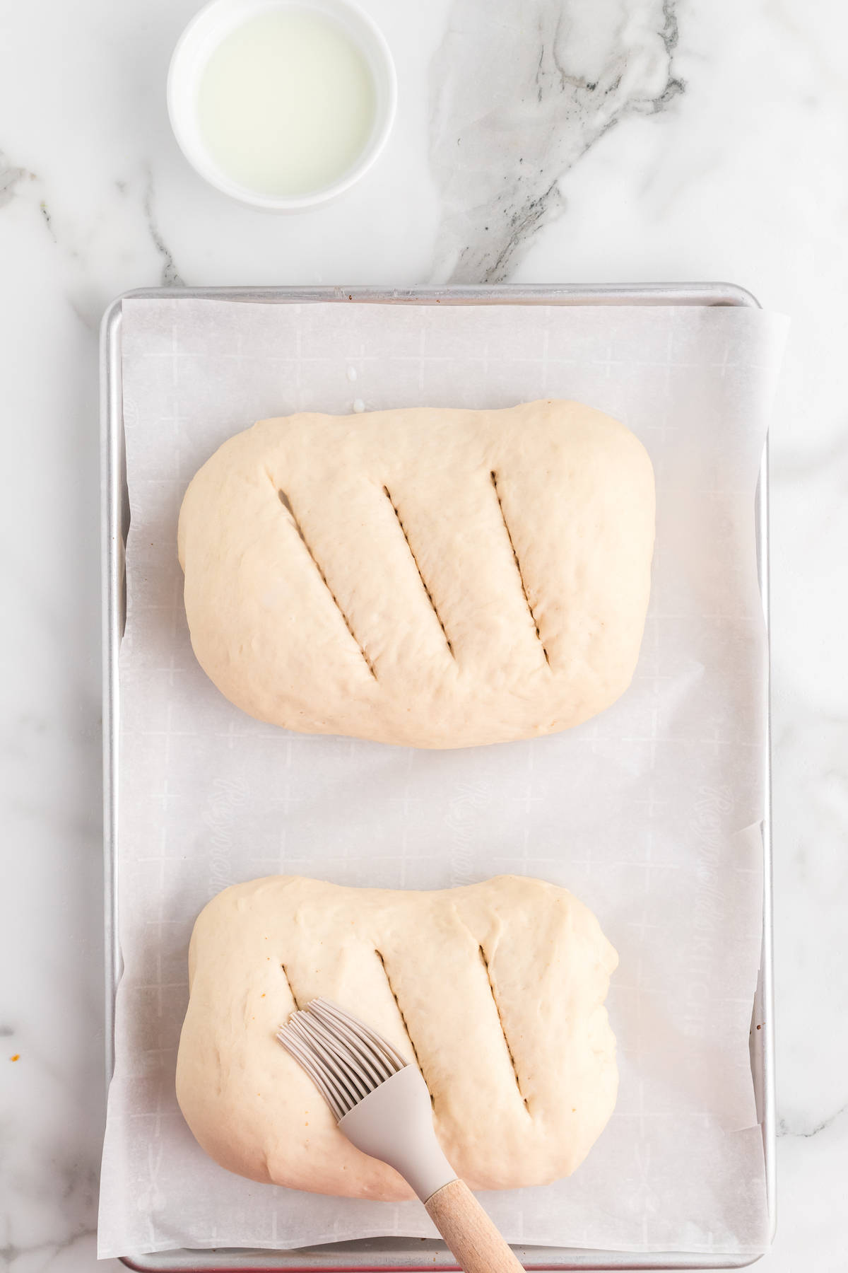 spreading milk mixture over top of the bread.