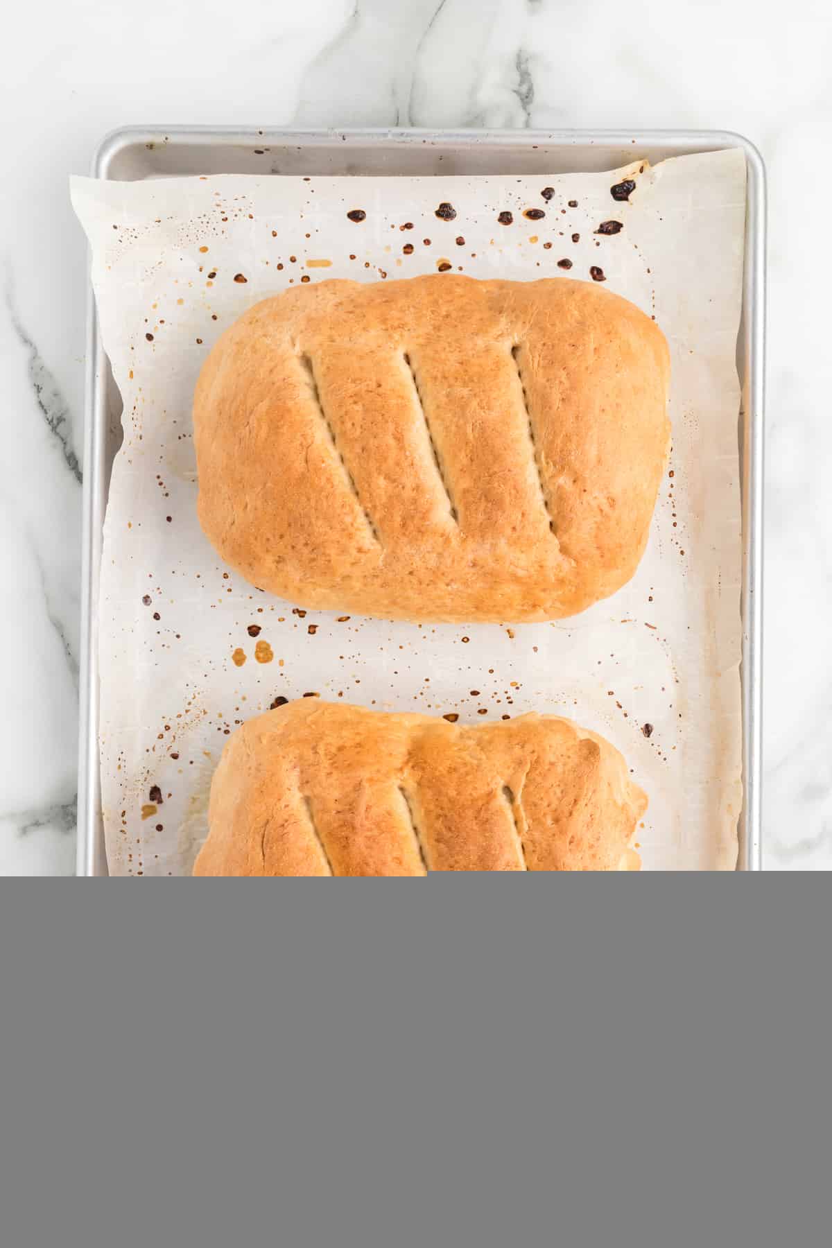 fresh baked bread loaf on a parchment paper lined baking sheet. 