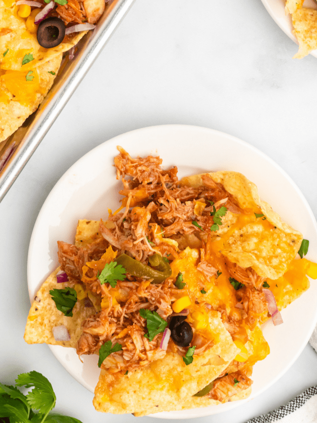 bbq chicken nachos on white plates with cilantro garnish