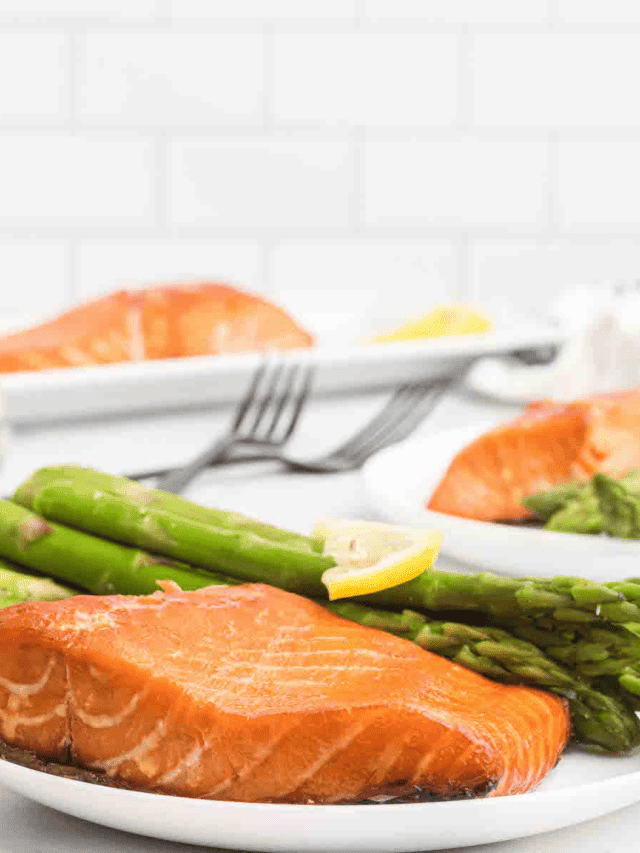white plate of traeger salmon with asparagus behind it.