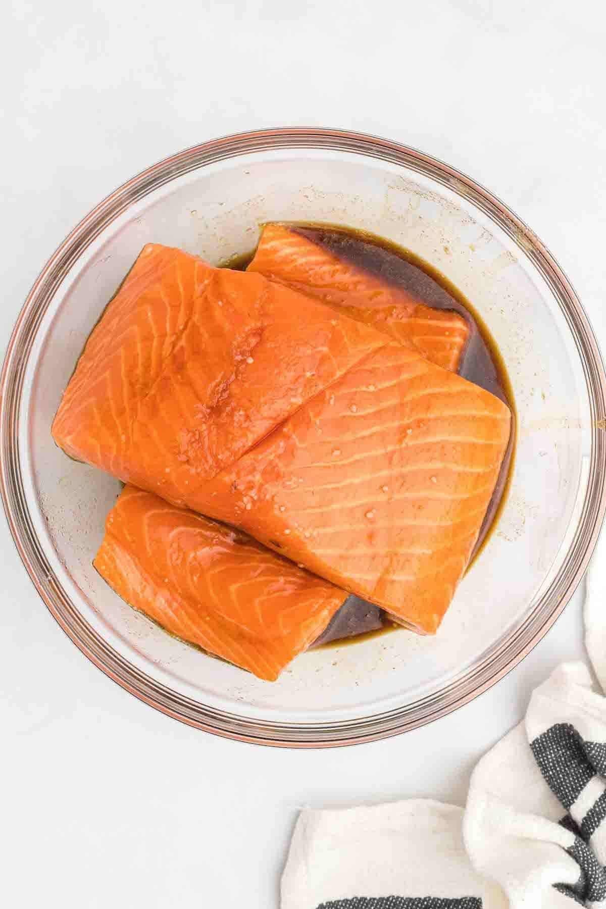 adding the salmon to the marinade in the large glass bowl