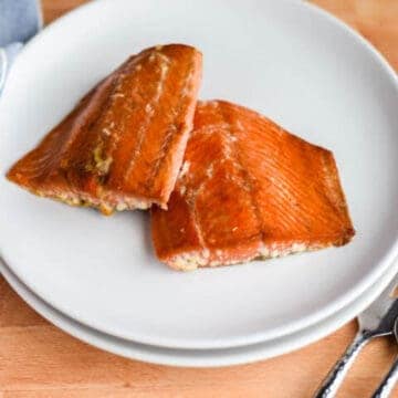 two finished Traeger grilled salmon pieces on a white plate