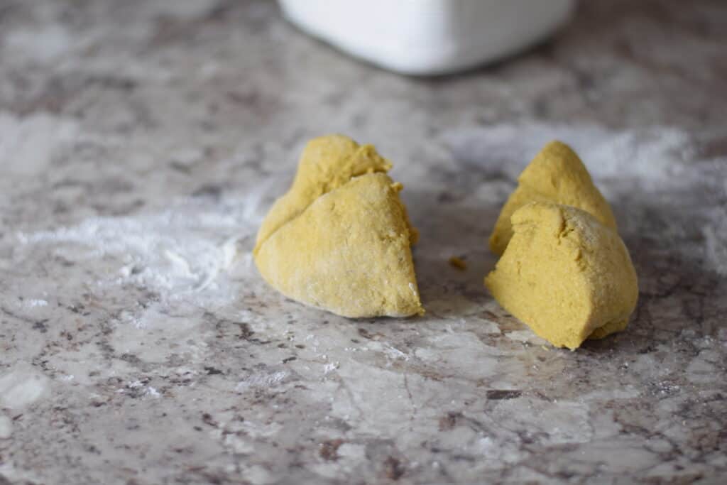 pasta dough divided into four even pieces on a counter top