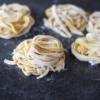 homemade pasta noodles resting into nest piles and drying on black counter top