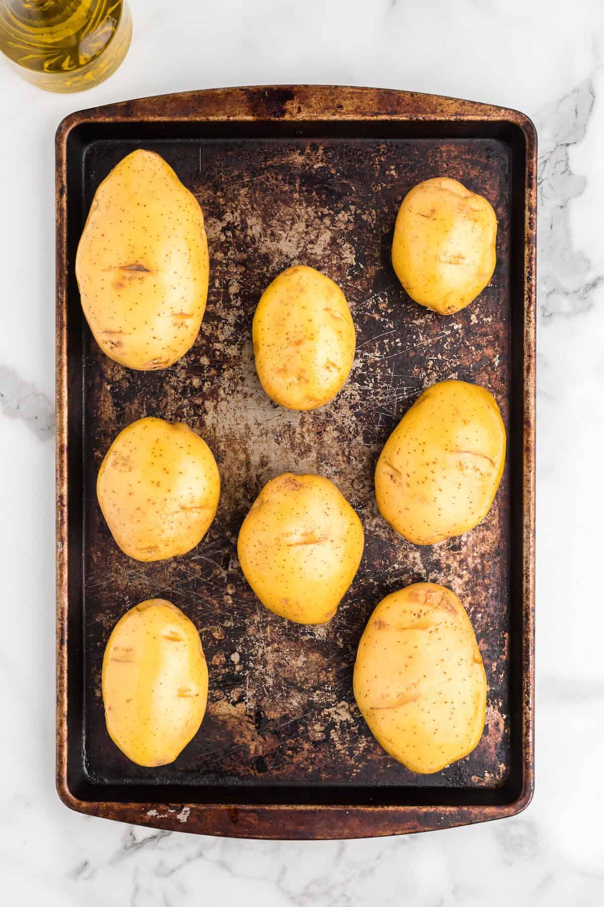 Yukon gold potatoes on a baking sheet with oil rubbed on sides.