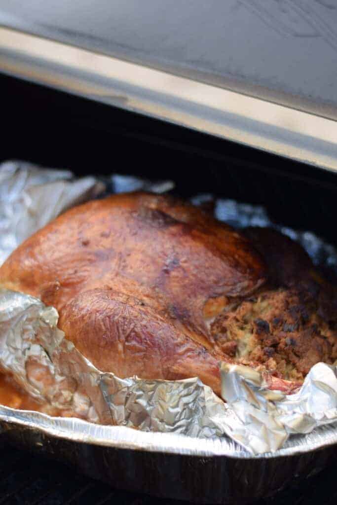 turkey in a roasting pan and on the traeger grill 