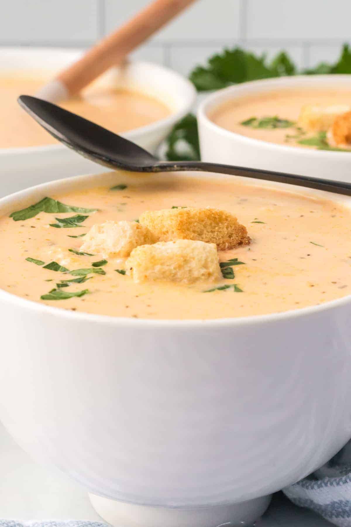 white bowl of creamy acorn soup with croutons on top