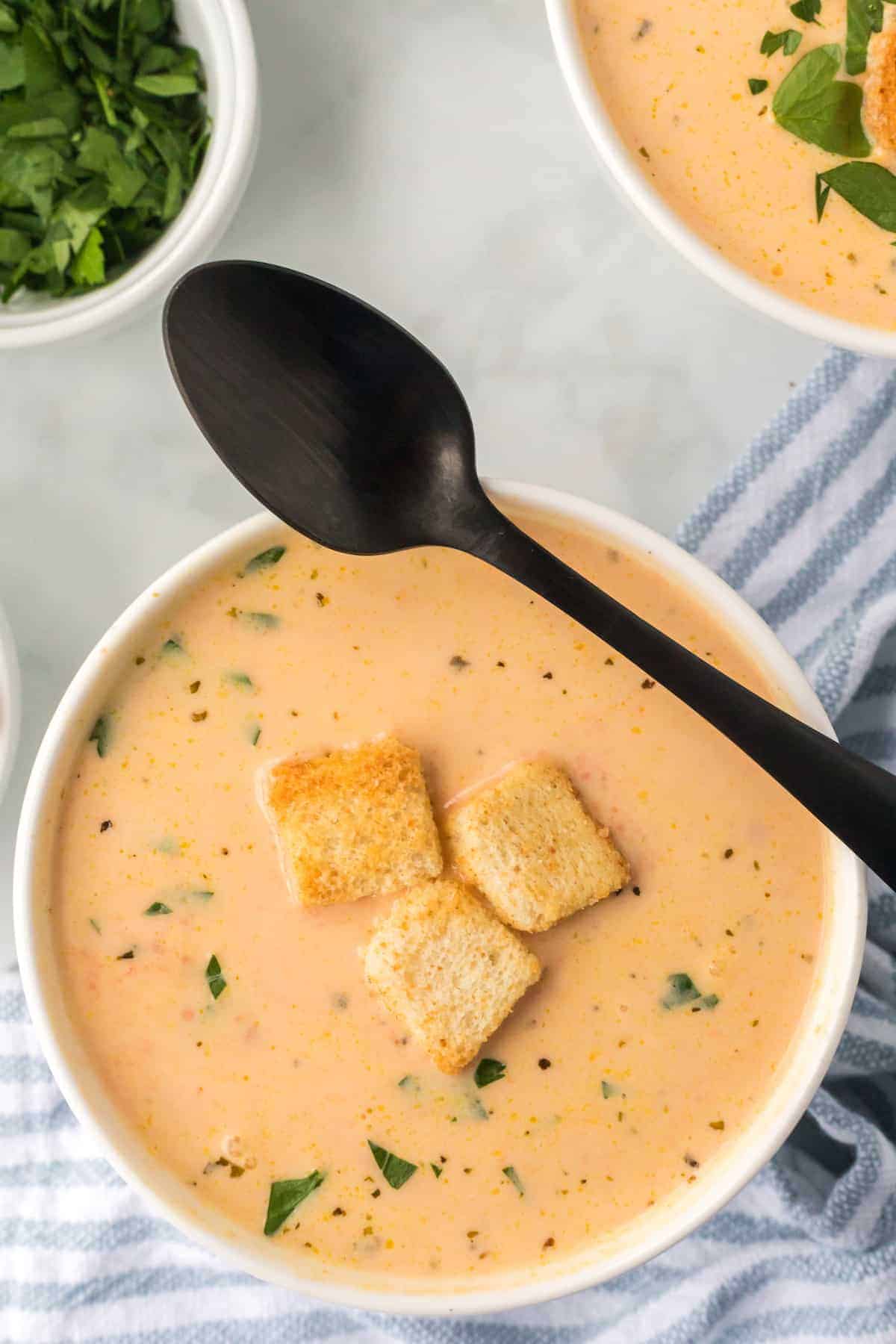 bowl of creamy carrot soup with black spoon resting on the top