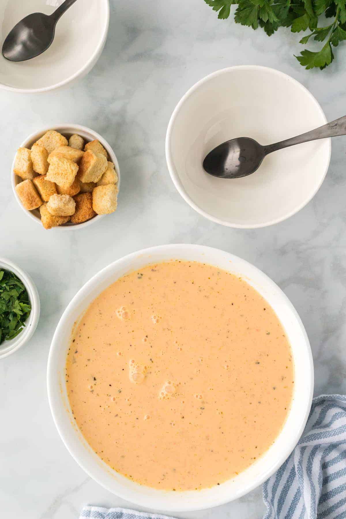 finished soup in a white pot with bowls and spoons to the side