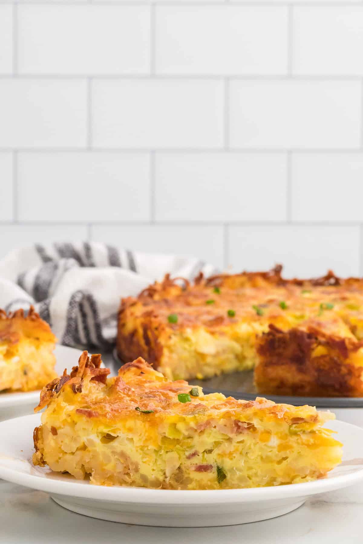 slice of the bacon and leek hash brown quiche on a white plate.
