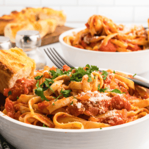 two white bowls of pasta noddles and homemade Italian San Marzano tomato sauce.