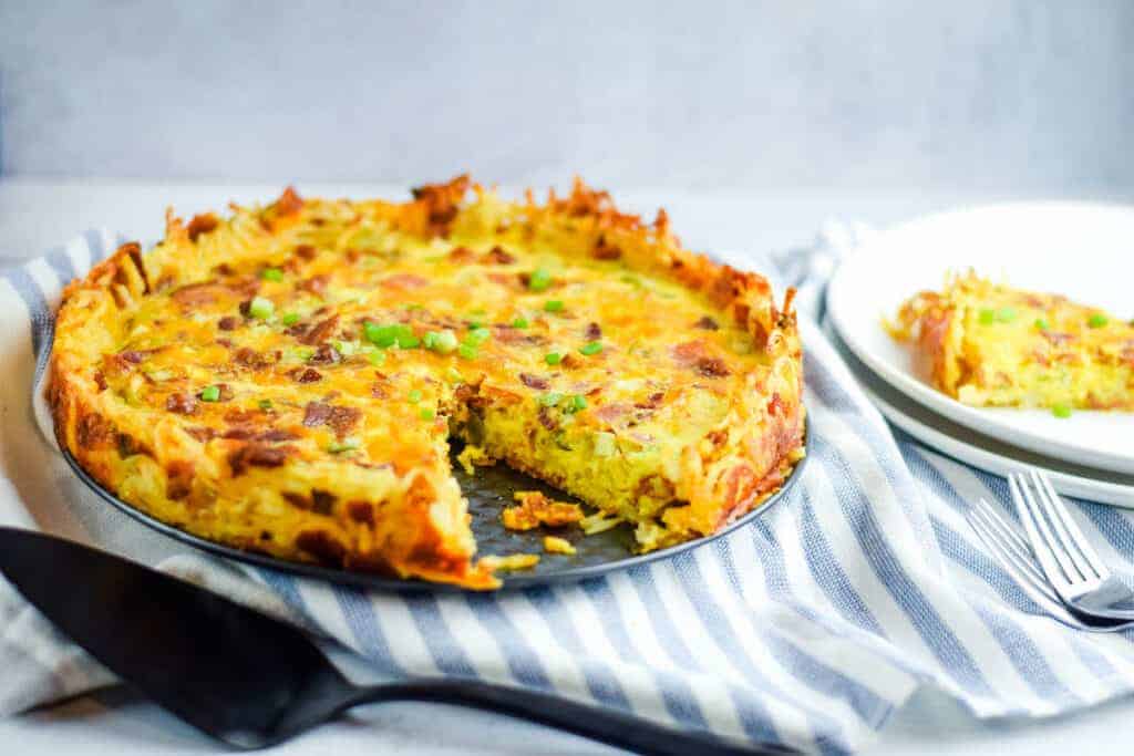 finished hash brown quiche on a dining table with place serving utensils