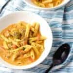 two bowls of meatball soup in white bowls with black spoons