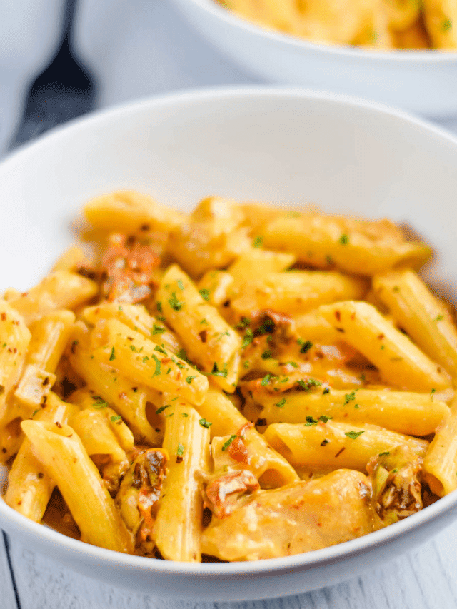 white bowl of finished sun dried tomato pasta with a black fork in background