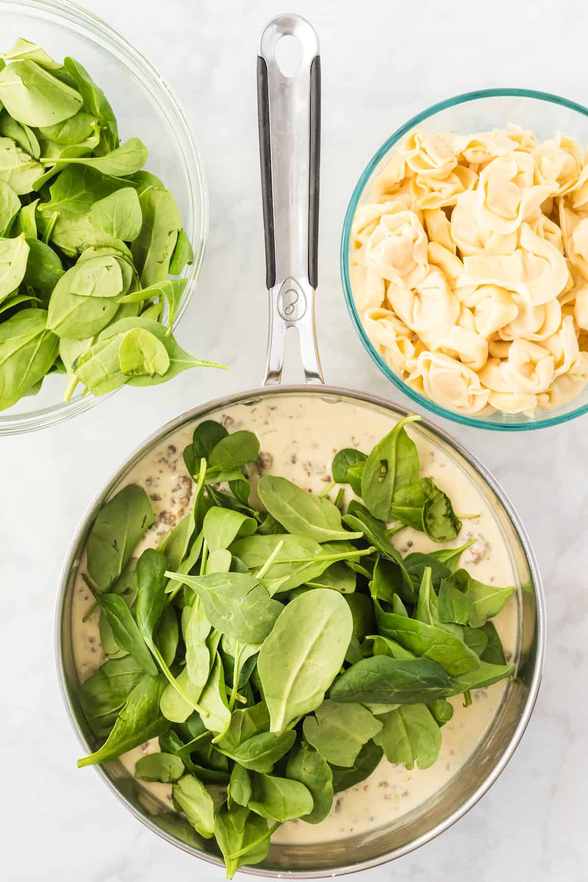 adding the baby spinach to the skillet with the cream sauce