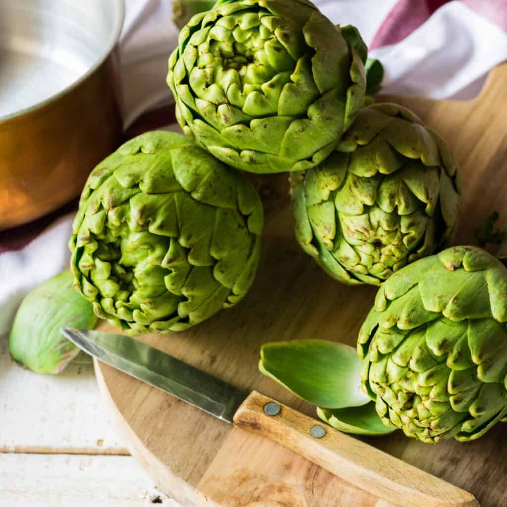 harvested artichokes on a cutting board in the kitchen 