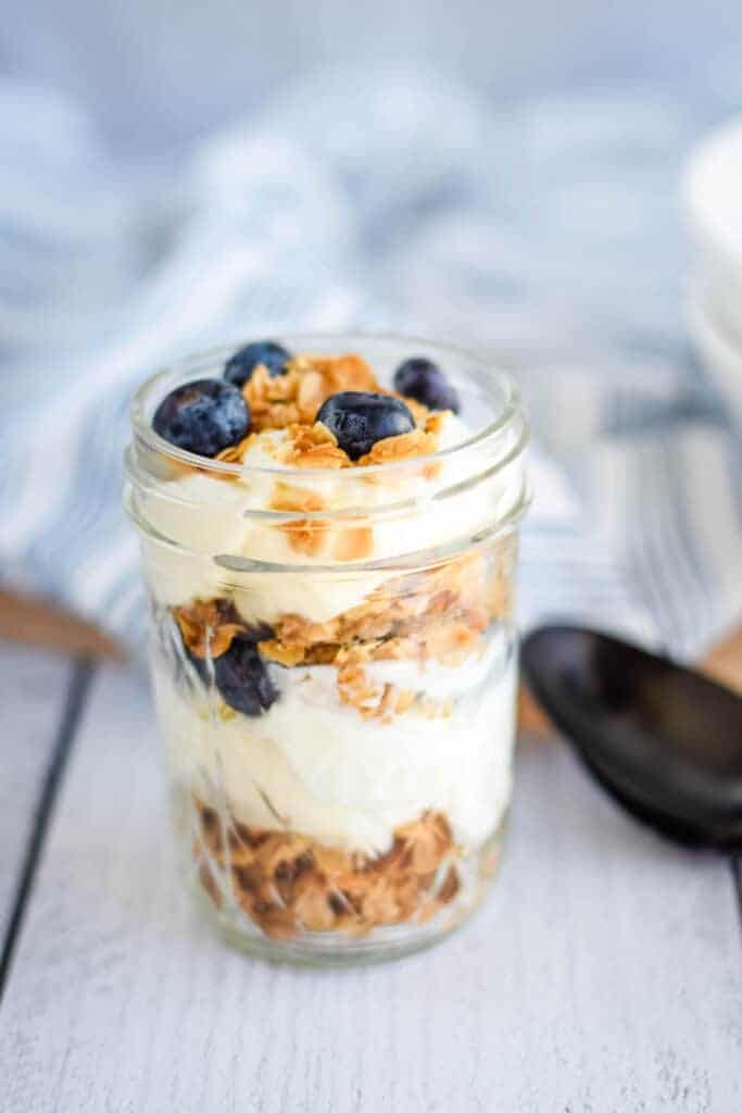healthy homemade granola layered in a pint sized mason jar with fresh blueberries and yogurt