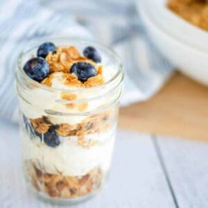 homemade granola layered in a pint mason jar with yogurt and fresh blueberries