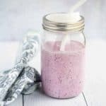 homemade blueberry and banana smoothie in a mason jar with a white straw