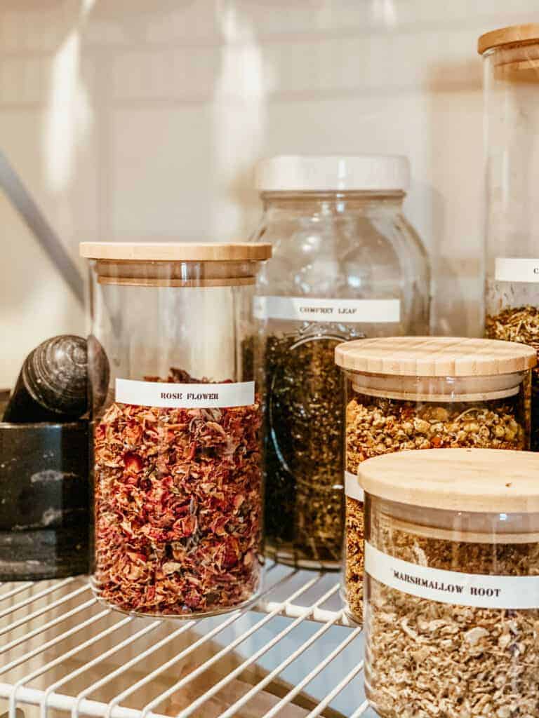 close up of dried herbs and rose petals in storage jars 