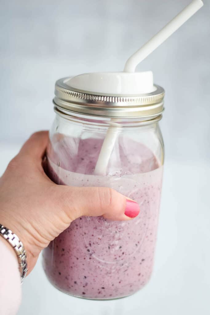 holding a mason jar filled with fresh gut healthy smoothie