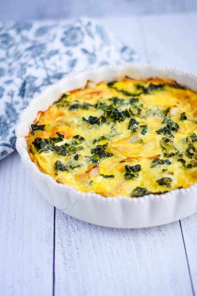 kale quiche in a white pie dish